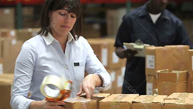 Factory Worker Sealing Packages With Tape