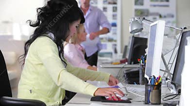 Woman Working At Desk In Busy Creative Office