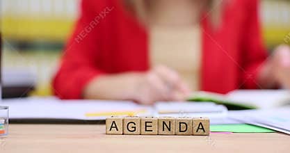 Wooden cubes arranged in straight line form word AGENDA at lady