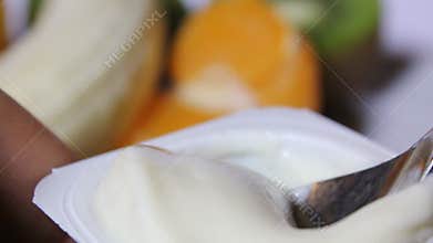 A person eats a fruit yogurt