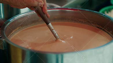 Close-up of soup being stirred in large pot at street market