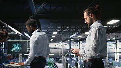 Programmers on data center industrial platform checking code on tablet