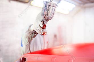 Spray gun and worker painting a car
