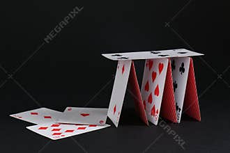 Collapsed house of playing cards on black background