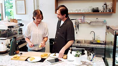Small business owners prepare fresh pastries and collaborate at their cozy cafe counter. The image reflects teamwork,