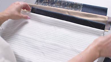Woman in sewing production selects the necessary materials for sewing batches of clothing