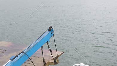 Close up of crane connect with ramp on cargo vessel heading towards to the port