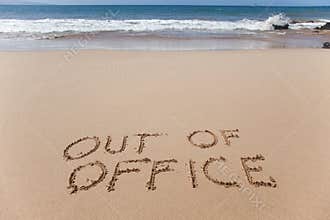 Out of office written in the sand on a beach