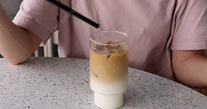 Woman putting a black straw in iced latte macchiato