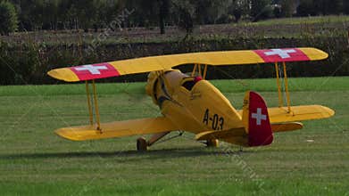RC model of a Bucker Bu 133 Jungmeister biplane taxiing on a grass field