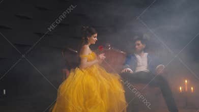 Happy loving romantic married couple sitting on antique sofa. Halloween costume yellow vintage dress, blue tuxedo