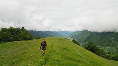 Aerial of solo traveler backpacking in alpine meadows. Hiker enjoys scenic mountain views, green landscapes. Active
