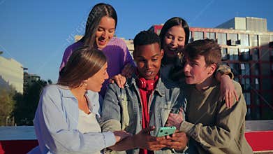 A joyful group of diverse friends enjoying a moment together outdoors, smiling and using a cellphone to capture memories
