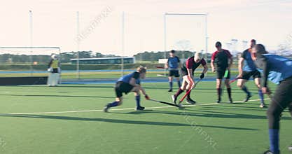 Playing field hockey, male athletes competing on outdoor school field