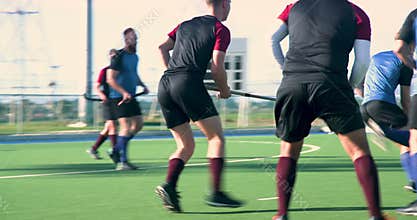 Playing field hockey, men competing on outdoor field, teamwork and action