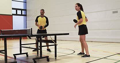 Playing table tennis, man and woman in sportswear competing in gym