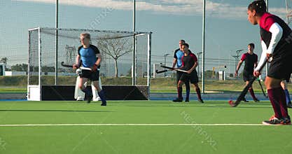 Playing field hockey, male players competing in outdoor match, focusing on game