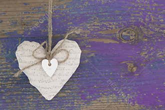 Hanging heart and purple wooden background in country style.