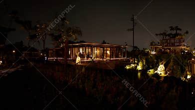 Tropical resort at night with illuminated bungalow and palm trees