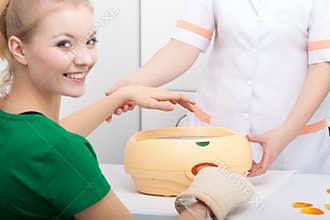 Happy woman in beauty spa salon with paraffin wax bowl