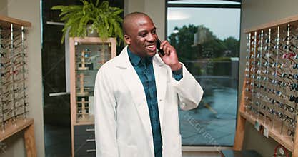 Optometrist Smiles While Talking on The Phone in His Eyeglass Shop