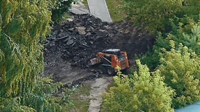 Skid steer loader removing asphalt from road construction site