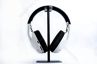White headphones hanging on a stand against white.