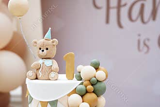 Close-up of teddy bear-themed first birthday cake with fondant details, balloons, and pastel decorations.