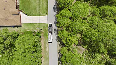 American garbage truck picking up trash bins on rural street side.