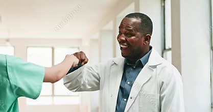 Doctor and Nurse Fist Bumping in Hospital Hallway, Showing Teamwork and Positive Communication
