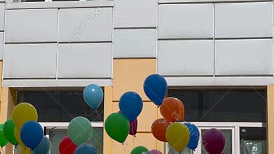 Colorful balloons floating against building facade