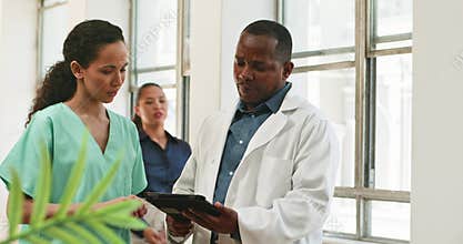 Diverse Medical Team Collaboration: Doctor and Nurse Discuss Patient Care Using Digital Tablet in Hospital Setting