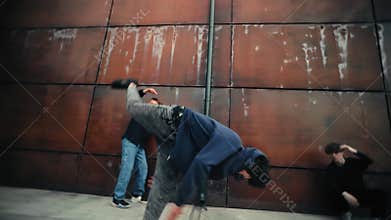 Young male dancers performing street dance choreography, displaying urban dance skills near contemporary building facade