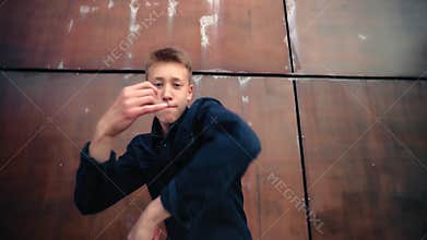 Young male dancer executing dynamic hip hop choreography, moving with expressive hand gestures. Standing confidently