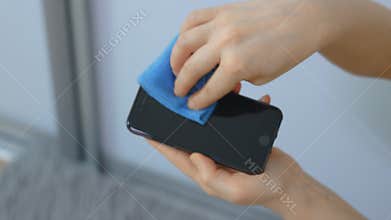 Person with an unrecognizable face to cleanse the mobile phone screen