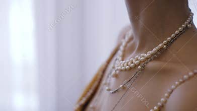 Woman wearing pearl necklaces and gold dress. Clothing and accessories of the 20th century.