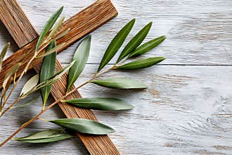 Brown rustic cross and olive branches on wooden background