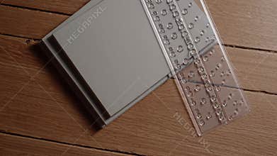 Braille alphabet guide resting on notebook on wooden desk