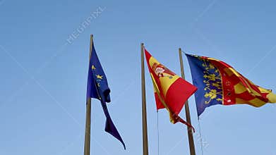 European, Spanish, and Catalan Flags Elegantly Displayed Against a Clear Blue Sky