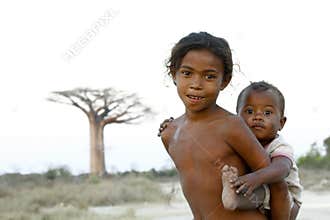 Madagascar-shy and poor african girl with infant on her back