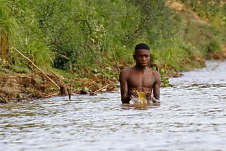 African poor man taking a bath in river