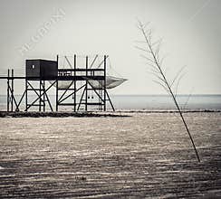 Fishing hut stands on stilts during low tide near the ocean in early morning light