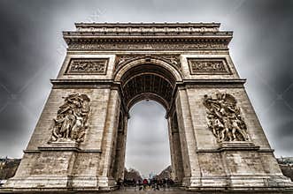 Majestic Arc de Triomphe in Paris Under a Dramatic Overcast Sky, Showcasing its Grandeur and Historical Detail