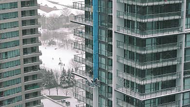 Urban cleaning scene. Efficient workers on highrise cleaning platform view snowy courtyard with sleek architecture
