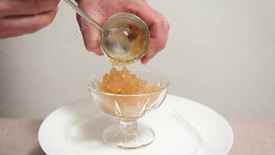 Light fish roe in glass container scooped with teaspoon close-up gourmet appetizer caviar delicacy home kitchen serving