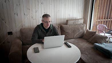 A man works on a laptop in the interior of a village house.