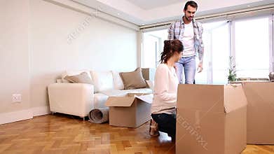 Attractive couple unpacking boxes in their living room