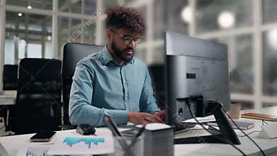 Concentrated Arabian business man working using computer corporate technology software at table with paper diagram stats