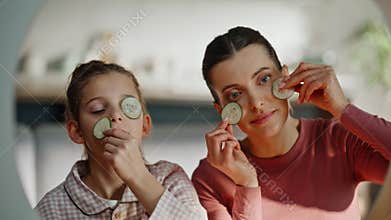 Family making cucumber masks putting slices on eyes together at bathroom closeup