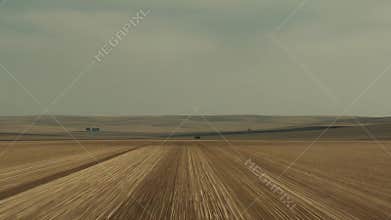 Arable land extending to horizon under cloudy sky